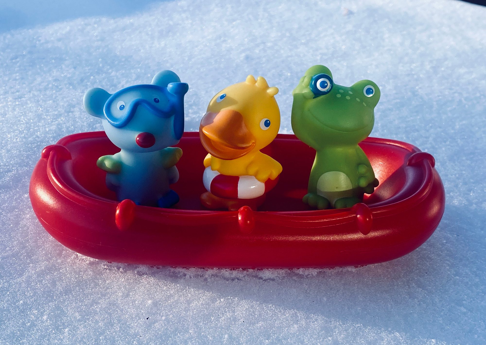 Drei bunte Tierfiguren in einem roten Boot.